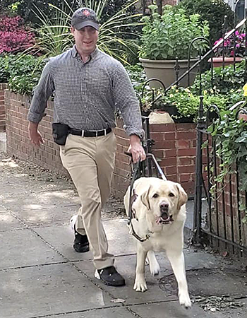 In June of 2021, Pat and Hogan are in motion, taking quick-paced strides, as they walk past the beautiful, raised flower beds of D.C. row houses. Pat is smiling and Hogan sneaks a glance at the camera.  