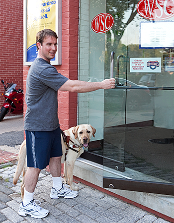 Pat, wearing a grey shirt, shorts, and tennis shoes, heads into the gym on Capitol Hill. Galahad looks forward to a snooze while Pat works out.